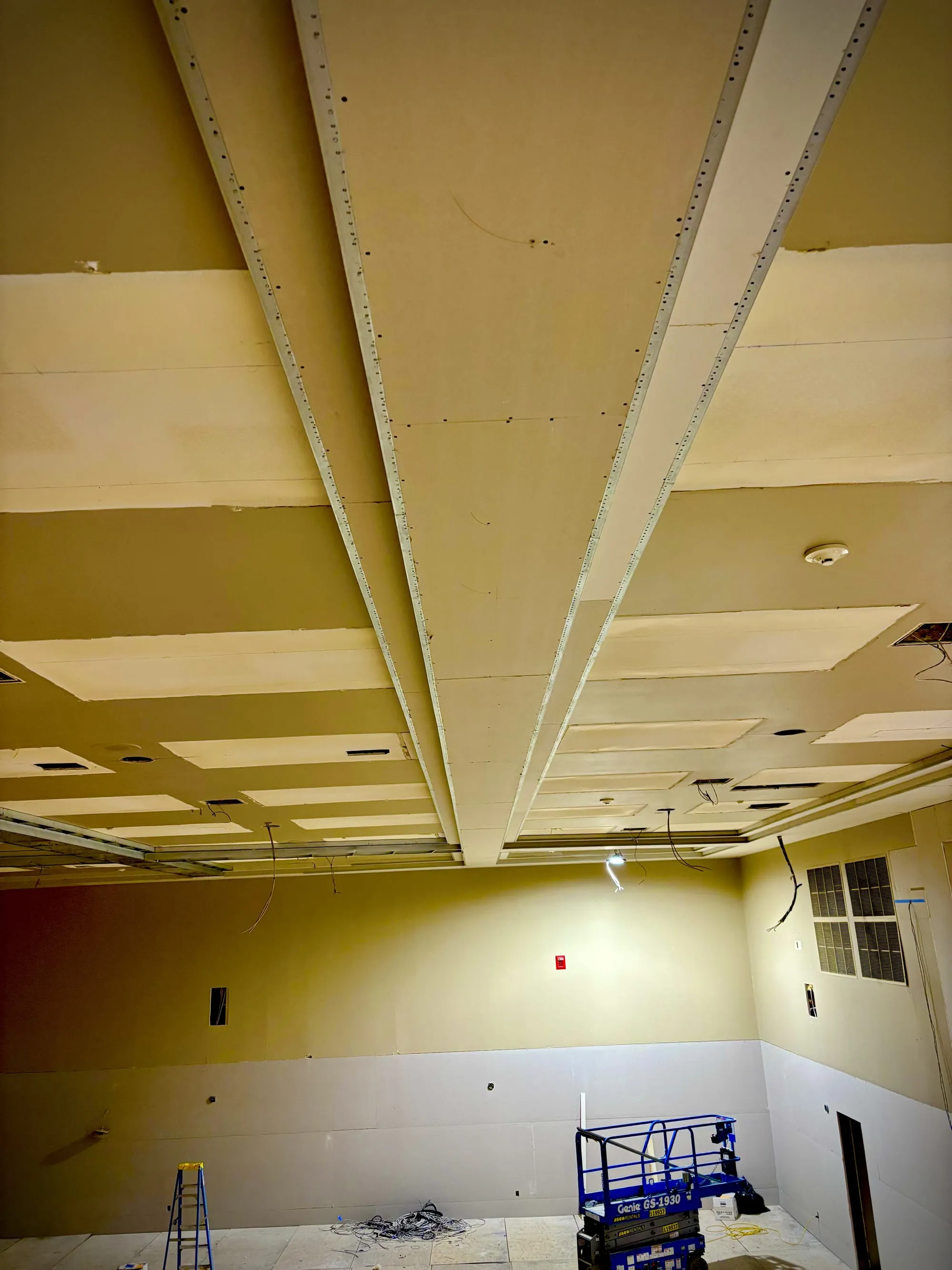 Drywall-wrapped beams and ceiling framing running the length of a commercial hall